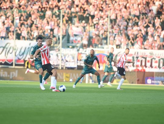 Piłkarz Cracovii pod presją zawodnika Pogoni zagrywa piłkę.