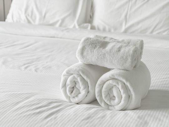 Na zdjęciu ręczniki hotelowe położone na pościelonym łóżku