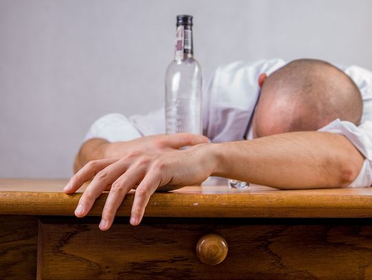 Na zdjęciu mężczyzna po libacji alkoholowej z butelką wódki w ręku