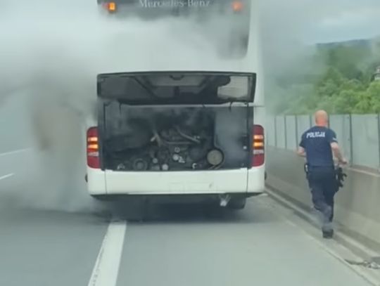 Na zdjęciu policjant gaszący pożar autokaru na Zakopiance w Stróży