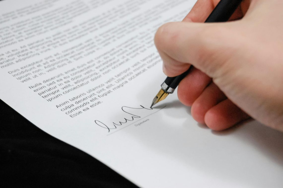 Na zdjęciu osoba podpisująca akt notarialny